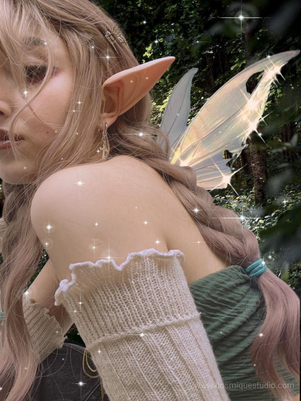 A blonde fairy grunge aesthetic girl with elf ears, earrings and wings. 