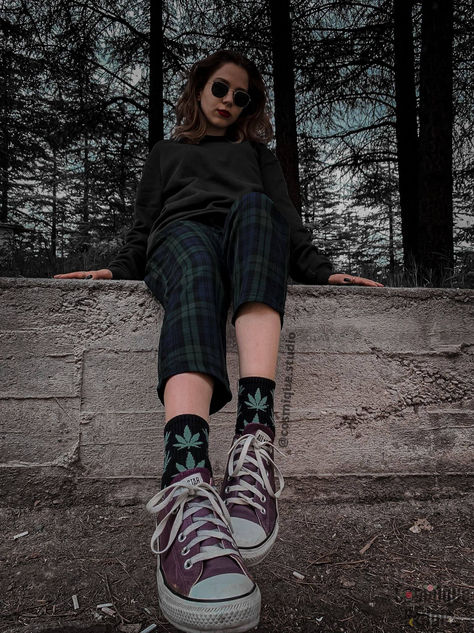 grunge aesthetic girl in the forest, wearing weed socks and leather purple converse under a plaid baggy green pants and a green hoodie 